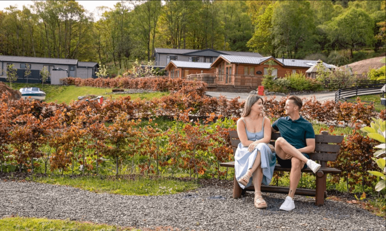 Image of a couple sat together on a bench at a caravan park