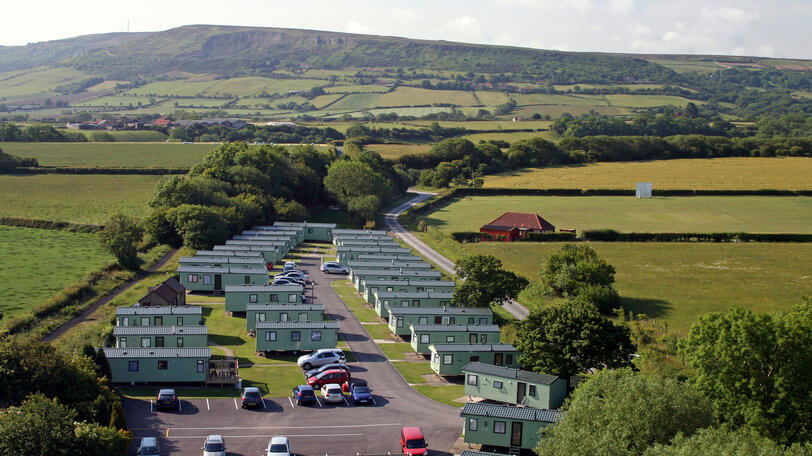 view of multiple static caravans side by side in a sunny field