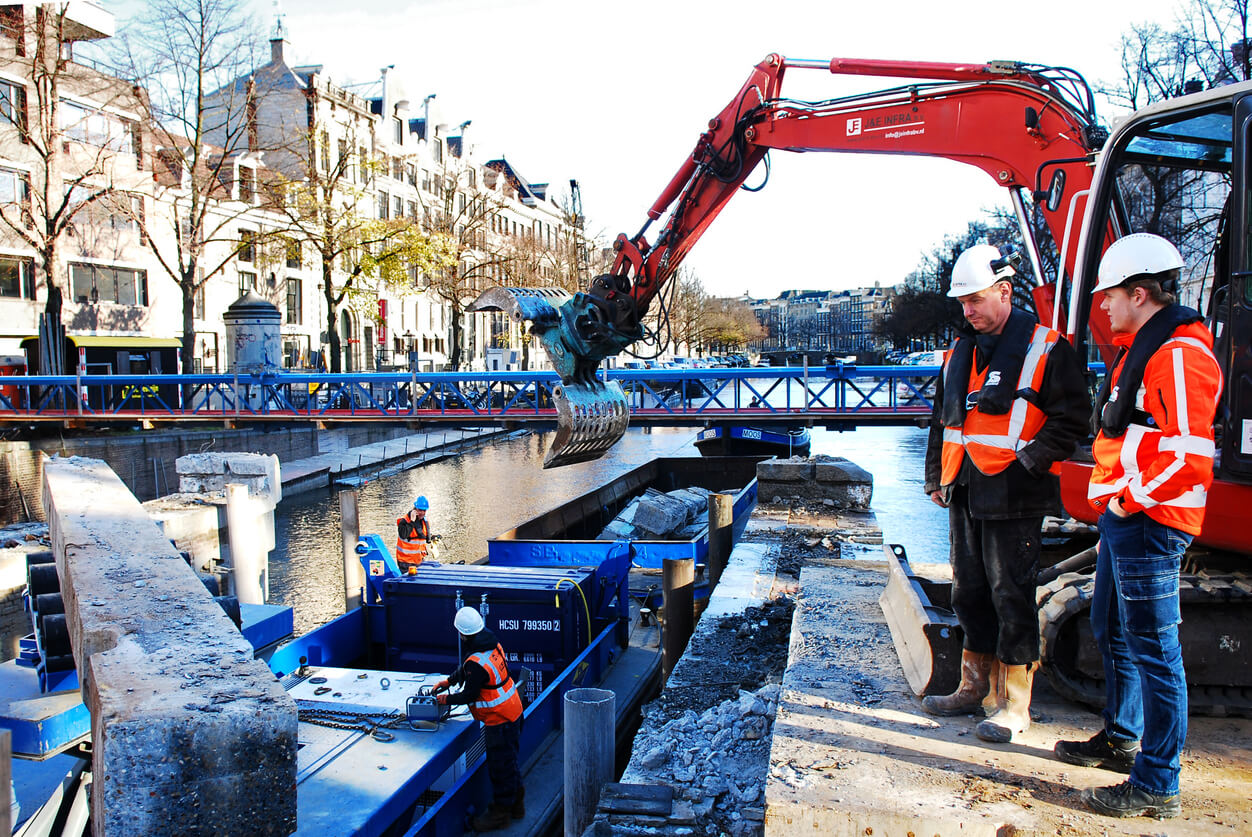 two maintenance workers using a machine to work on a narrowboat