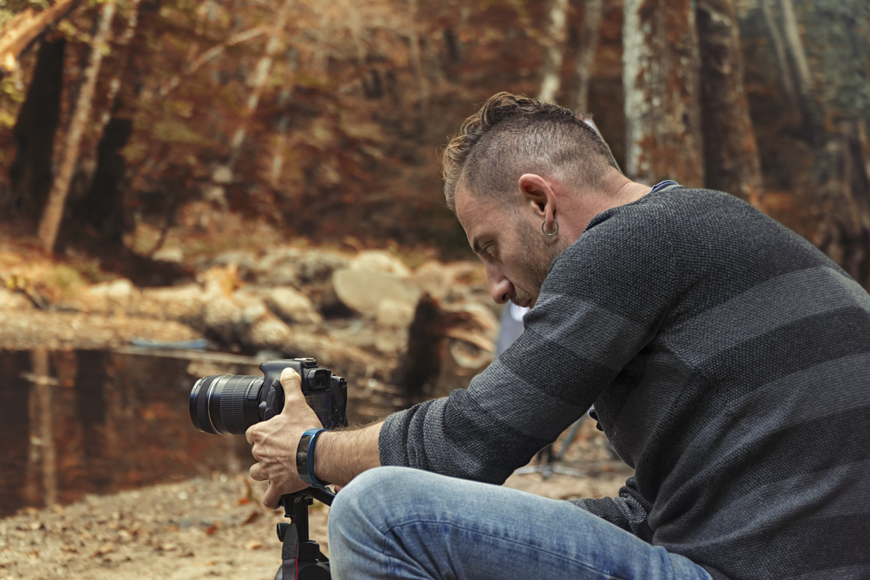 image of a person in a striped jumper taking woodland photography with a tripod