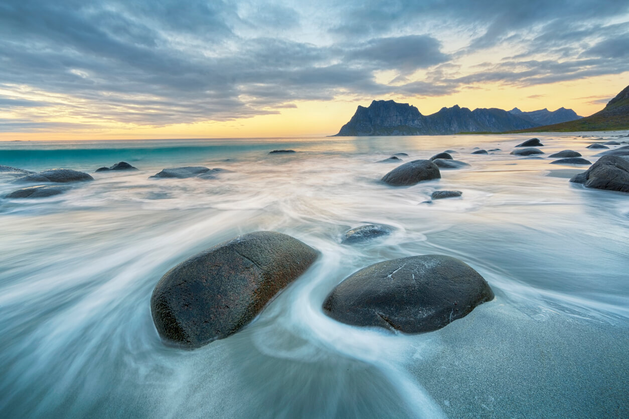 long exposure photography image of rocks on a beach at sunset