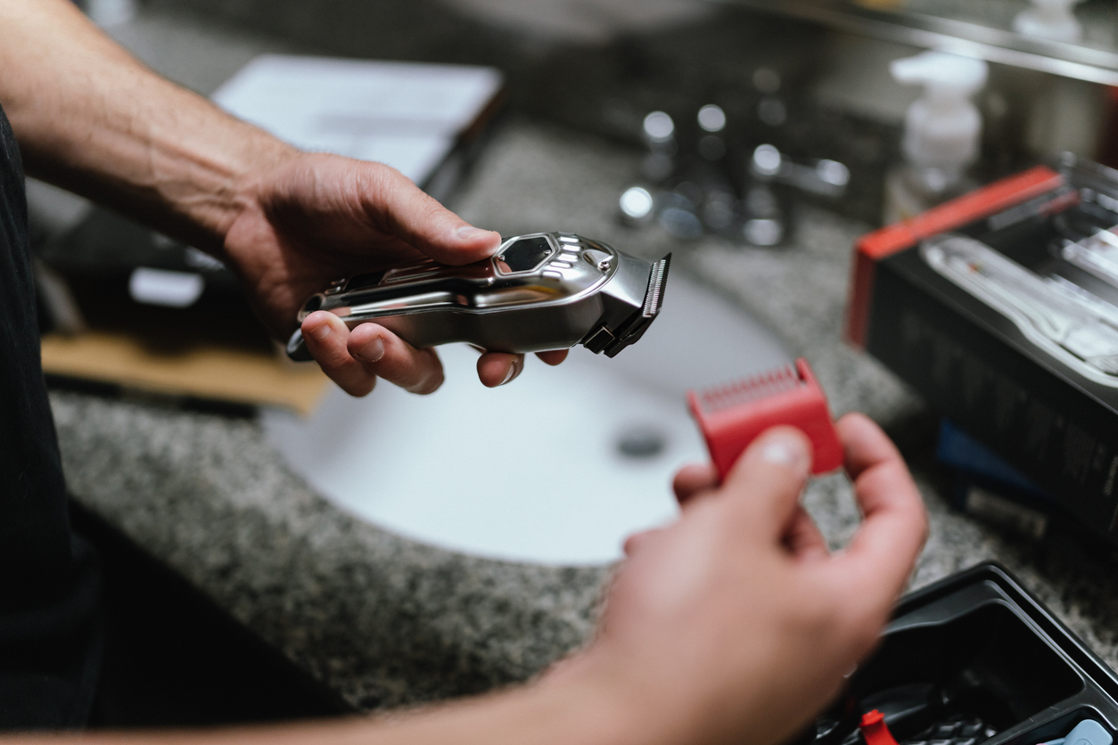 Man cleaning hair clippers and guard