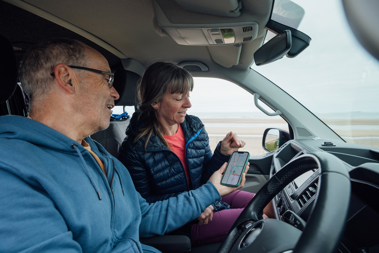 Couple using motorhome satnav app on phone while parked up